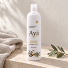 Ayä Olive body wash 500 ml bottle on a travertine bathroom ledge with linen towel and olive sprig