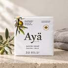 Ayä Olive bar soap 3x90g pack on a limestone washstand with linen towel and olive sprig
