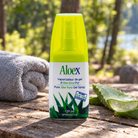 Aloex Aloe Vera topical gel spray 120ml on a wooden campsite picnic table in dappled sunlight beside a cut aloe vera leaf